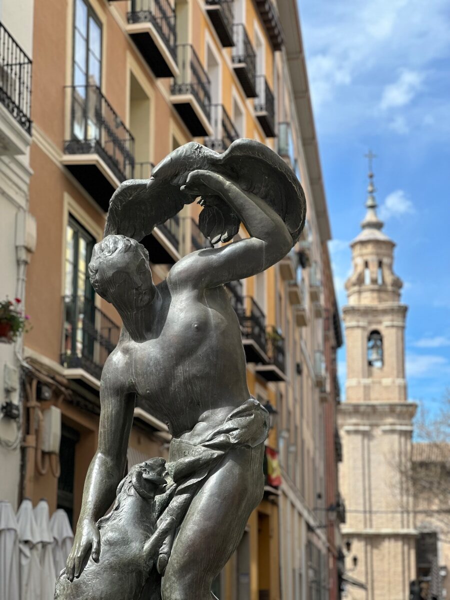 a statue of a man holding a hat in front of a building